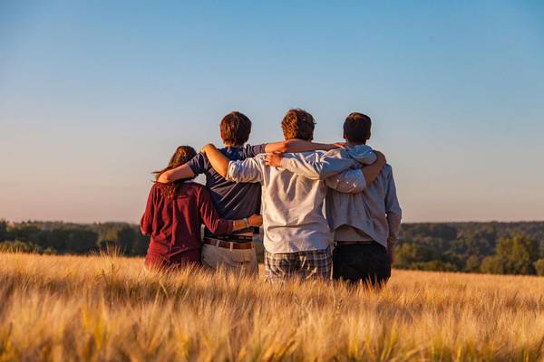 Vier Jugendliche stehen Arm in Arm auf einem Feld